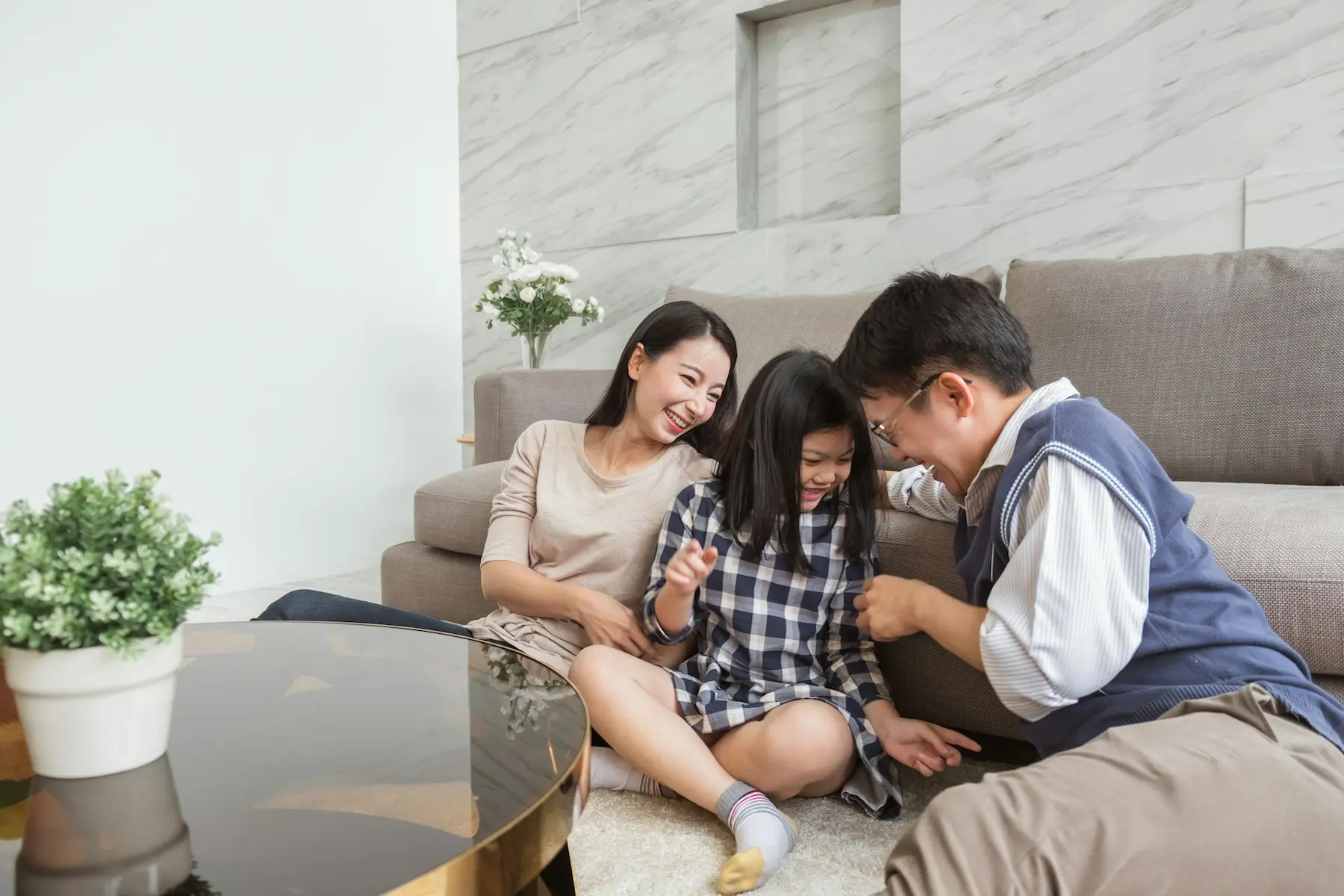 A happy family comprising a man, his wife and daughter all playing together in their living room